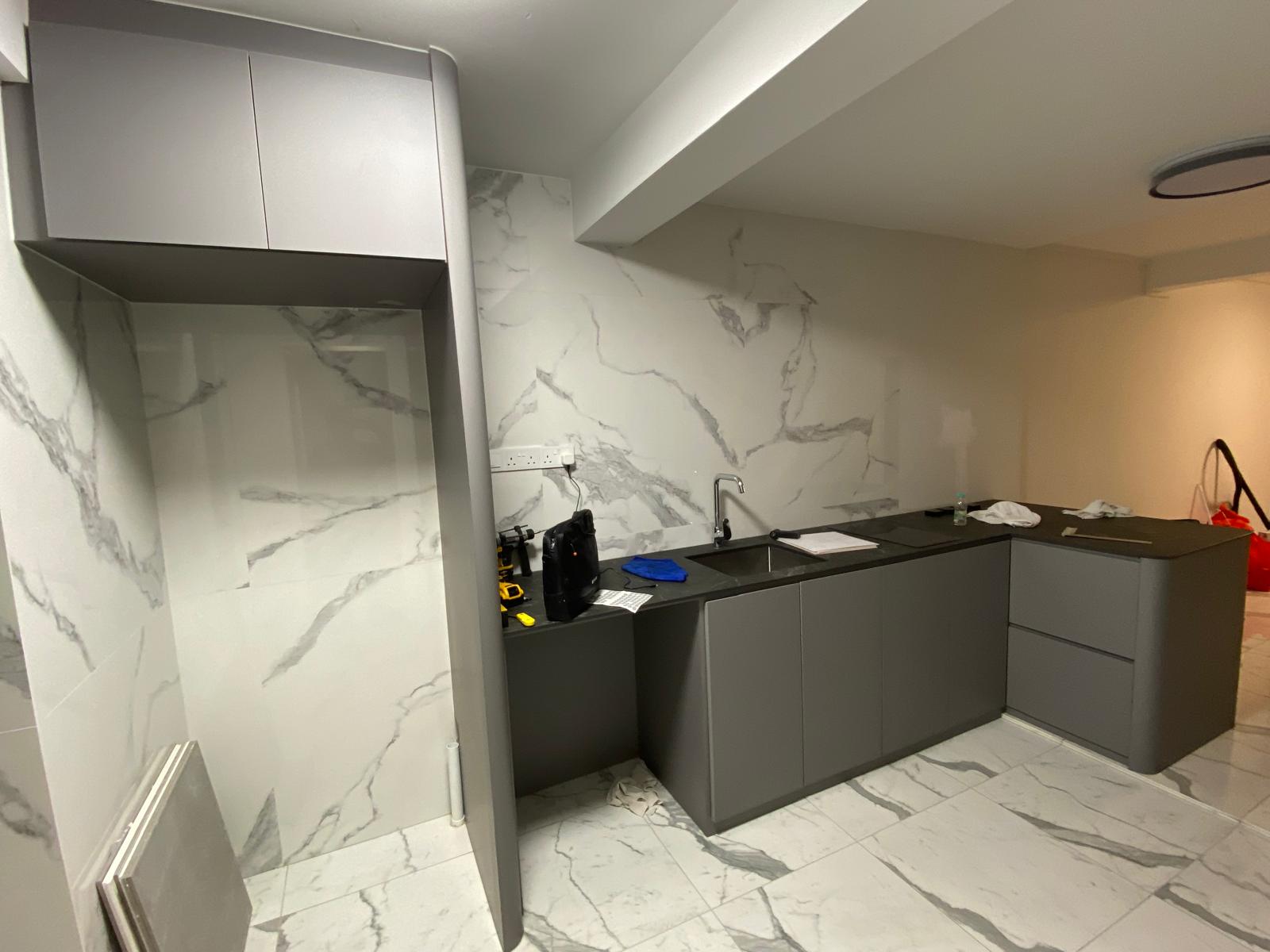 Kitchen with full-height marble-effect wall tiling, mid-installation